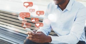 Businessman using social media with notification icons while sitting on a bench.